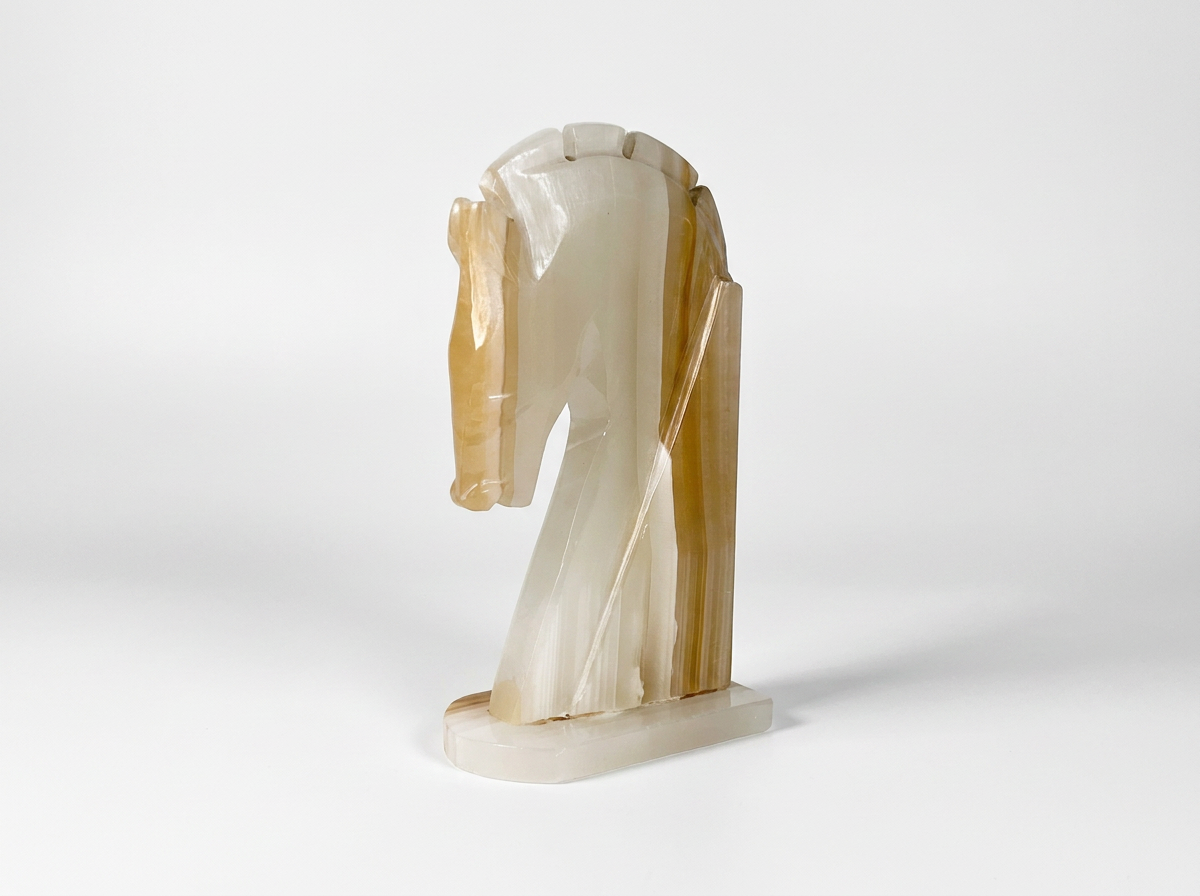 A sculptural horse head and neck figurine made from polished natural agate, featuring a cream and tan marbled pattern, set against a seamless light gray background.